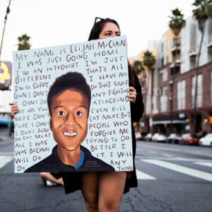 A person holds a sign at a candlelight vigil to demand justice for Elijah McClain on the one year anniversary of his death at The Laugh Factory on August 24